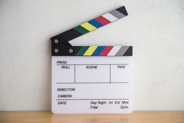 White cinema clapperboard on wooden table with white wall background. Film movies industry, theater, streaming online business concept.