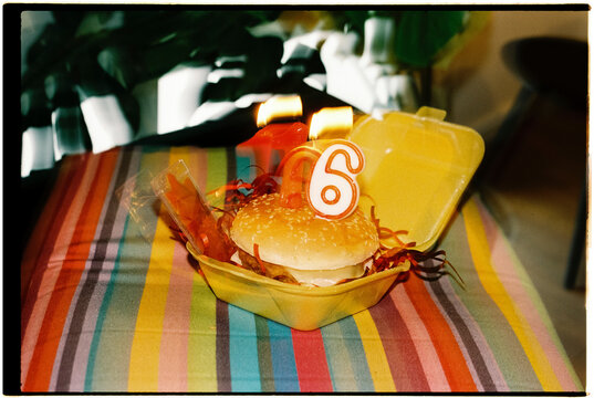 lit 16 number-shaped candles on burger, 35mm, with motion blur