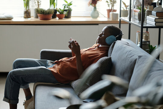 Gen Z Girl Resting on Couch with Headphones and Smartphone