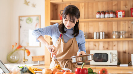 キッチンで料理をする女性（パスタを盛り付ける）