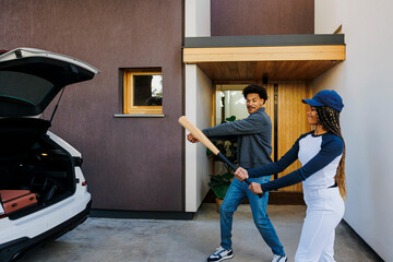 Family preparing for weekend baseball game outside modern home