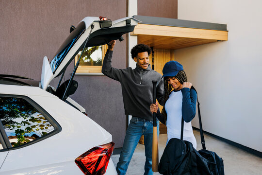 Father and daughter preparing for baseball game,loading gear into car
