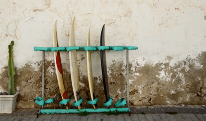 A rack of surfboards against a rustic rendered wall.
