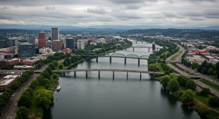 Fototapeta premium Aerial View of Portland Cityscape Featuring Bridges and Rivers under a Cloudy Sky in Oregon, USA, Showcasing Urban Architecture and Greenery
