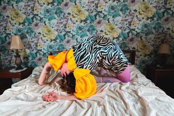 Young artist performing a backbend on bed in vintage room