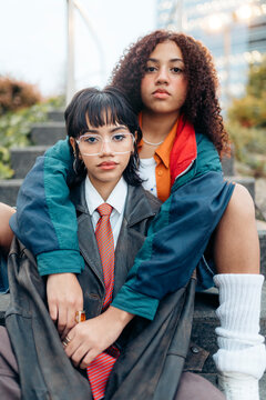 Two young women sitting on stairs wearing retro fashion