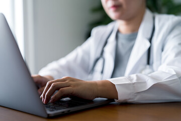 Doctor working on laptop with stethoscope at office. Online healthcare, digital patient records, telemedicine services, remote consultations and medical technology.