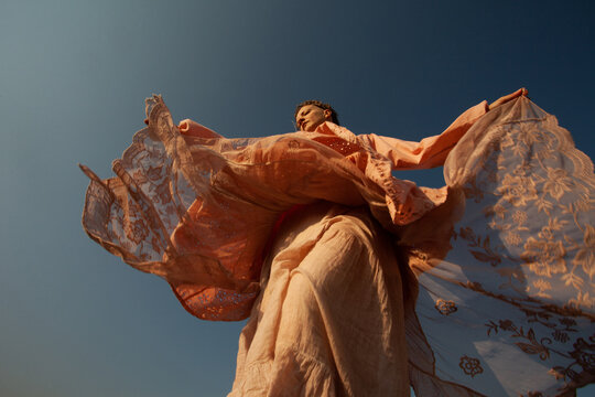 A girl in the pink dress dancing in the warm sunlight outdoors 
