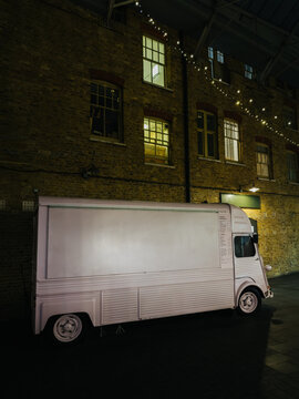 Vintage food truck under string lights against brick wall in London