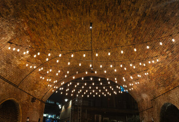 String lights illuminating brick archway in London at night
