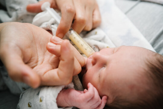 Mother feeding newborn baby with syringe after cesarean section