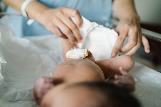 Nurse changing diaper of newborn baby after cesarean section