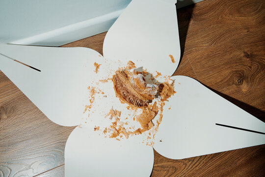 paper box with a piece of chocolate cake, on the floor