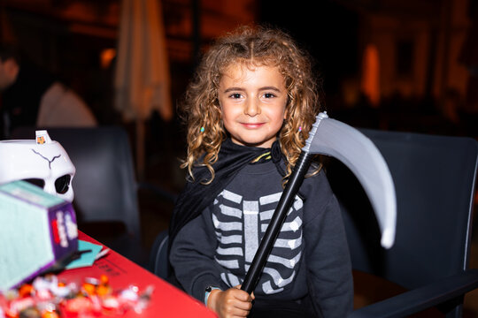 Smiling girl wearing halloween grim reaper costume holding