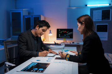 Asian business team analyzing financial data at night in office