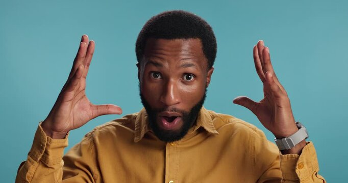 Explosion, news and face of black man in studio for surprise, announcement and notification. Promotion, wow and shocked with person on blue background for results, alert and mind blown emoji