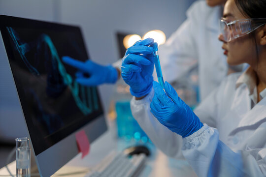 Scientists analyzing dna structure on computer and holding test tube