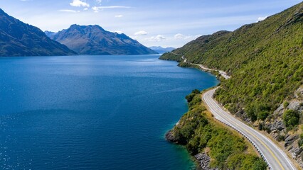 Obraz premium Scenic aerial view of winding road by blue lake.