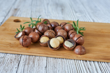 Shelled and unshelled macadamia nuts on wooden board