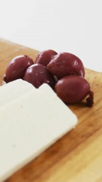 Slices of cheese with red olives and rosemary herbs