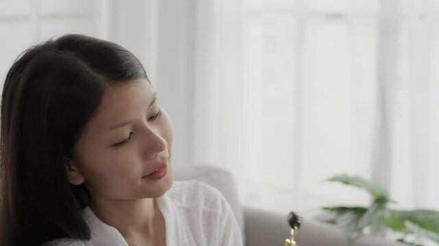 Asian woman in bathrobeses gua sha quarz lifting tool on face. Woman self massage with jade gouache scraper
