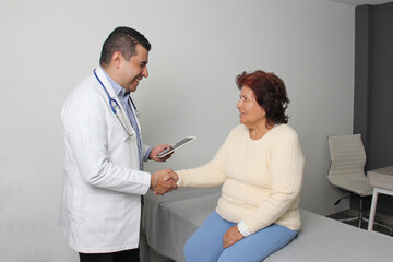 Obraz premium Elderly 80-year-old Latin woman visits the dark-skinned geriatric specialist medical doctor to check her health, they greet each other, laugh and hug