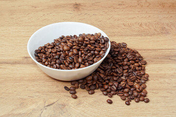 Coffee beans in a cup and scattered on the table.