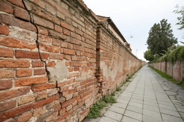 Weathered old brick wall with cracks and fading mortar, aged, building materials, crumbling