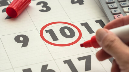 day ten of the calendar marked with a red pen. hand holding a red pen