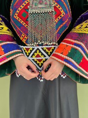 Colorful geometric patterned embroidery on black velvet. Close-up on the hands of an Iranian woman...