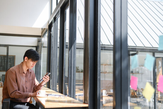Businessman working remotely while checking phone messages at a cafe