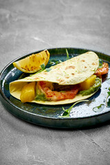 A close-up of a taco, showcasing the crispy texture of the tortilla and the juicy freshness of the shrimp. The creamy avocado adds a rich and indulgent flavor to the dish.