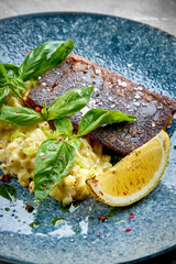 A vibrant and refreshing plate of grilled fish served with roasted vegetables and a side of sauce.