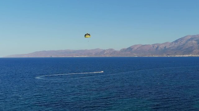 Aerial parasailing adventure over the blue sea with distant mountains in Crete Greece