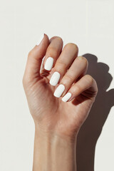 A close-up of a hand with white nails against a clean white background