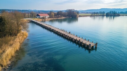 Obraz premium Aerial View of Tranquil Jetty Stretching into Serene Waters Surrounded by Scenic Landscape and Lush Vegetation in Utting, Bavaria