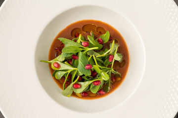 Purslane salad with olive oil and pomegranate in a white porcelain plate