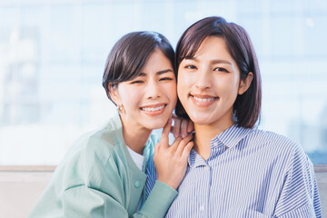 Obraz premium カメラ目線で顔を寄せ合ってパートナーとの愛情を確かめる30代の女性の同性のカップル