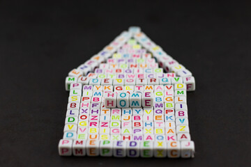 A close-up of letter blocks arranged to form a house shape. The word 