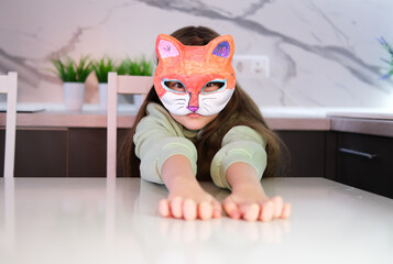 Young girl in casual quad style clothes with cat style mask. Cute child wearing a mask at home in...