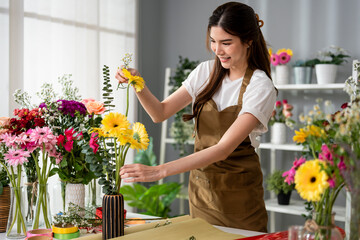 Asian young florist girl completing beautiful bouquet in flower shop. 