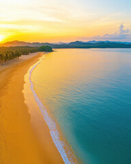 Aerial view of tropical beach at sunset with golden sand and calm water
