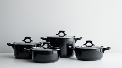 Four sleek black pots, varying in size, rest elegantly on a bright kitchen countertop. Their designs blend modern aesthetics with practical cooking solutions, perfect for any aspiring chef