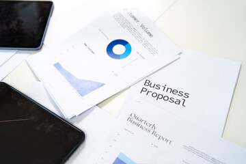 A business proposal document is prominently displayed alongside analytical charts and mobile devices, showcasing a professional workspace.