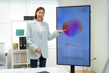 Fototapeta premium A professional woman presents information on a digital screen in an office setting, showcasing a colorful graphic.