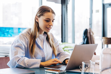 Young freelancer woman working on laptop in modern coworking space
