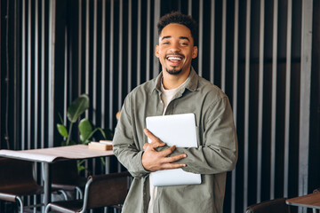 Smiling young manager holding laptop in modern office