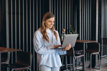 Young freelancer woman using laptop in modern cafe, working remotely