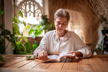 Woman engrossed in reading a notebook combination of indoor greenery, rustic textures, and soft...