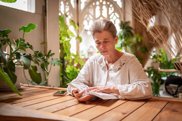 Woman engrossed in reading a notebook combination of indoor greenery, rustic textures, and soft...